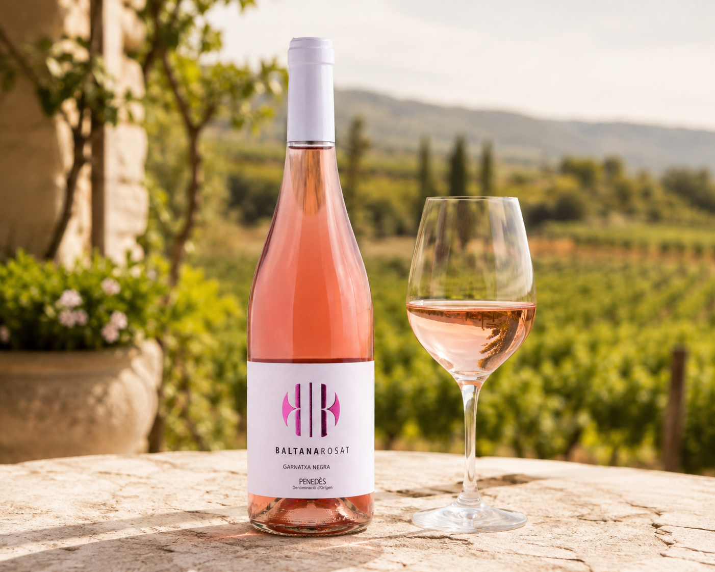 Baltana Rosado ecológico de Bodega Miquel Jané con copa de vino rosado y viñedos del Penedès